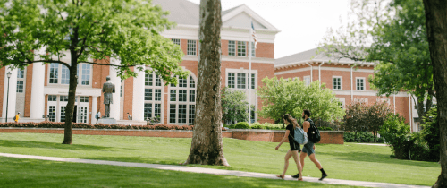 Students walking across campus in front of the Library